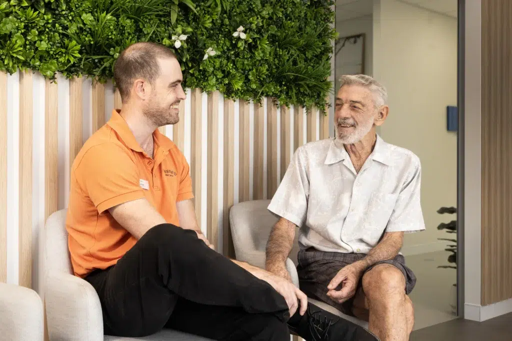 two males, one staff member and one client conversing while seated